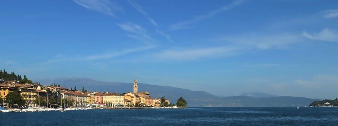 Trip Spanien beliebte Urlaubsziele am Gardasee -  Mit einer Fläche von 370 km² ist der Gardasee der größte See Italiens. Es liegt am Fuße der Alpen und erstreckt sich über drei Staaten: Lombardei, Venetien und Trentino. Die maximale Tiefe des Sees beträgt 346 m, er hat eine längliche Form und sein nördliches Ende ist sehr schmal. Dort ist der See von den Bergen der Gruppo di Baldo umgeben. Du trittst aus deinem gemütlichen Hotelzimmer und es begrüßt dich die warme italienische Sonne. Du blickst auf den atemberaubenden Gardasee, der in zahlreichen Blautönen schimmert - von tiefem Dunkelblau bis zu funkelndem Türkis. Majestätische Berge umgeben dich, während die Brise sanft deine Haut streichelt und der Duft von blühenden Zitronenbäumen deine Nase kitzelt. Du schlenderst die malerischen, engen Gassen entlang, vorbei an farbenfrohen, blumengeschmückten Häusern. Vereinzelt unterbricht das fröhliche Lachen der Einheimischen die friedvolle Stille. Du fühlst dich wie in einem Traum, der nicht enden will. Jeder Schritt führt dich zu neuen Entdeckungen und Abenteuern. Du probierst die köstliche italienische Küche mit ihren frischen Zutaten und verführerischen Aromen. Die Sonne geht langsam unter und taucht den Himmel in ein leuchtendes Orange-rot - ein spektakulärer Anblick.